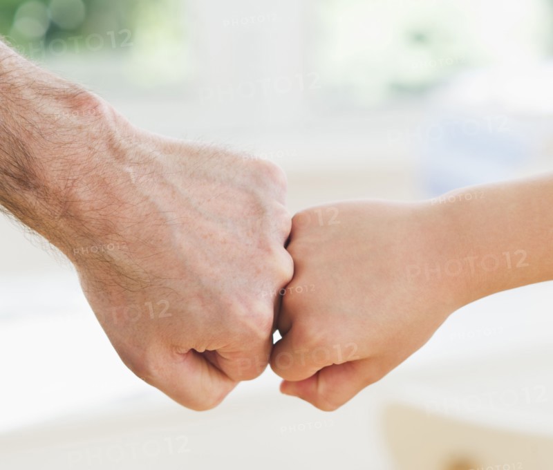 Close up of father's and son's (10-11 years) hands doing fist bump. 
Photo: Daniel Grill