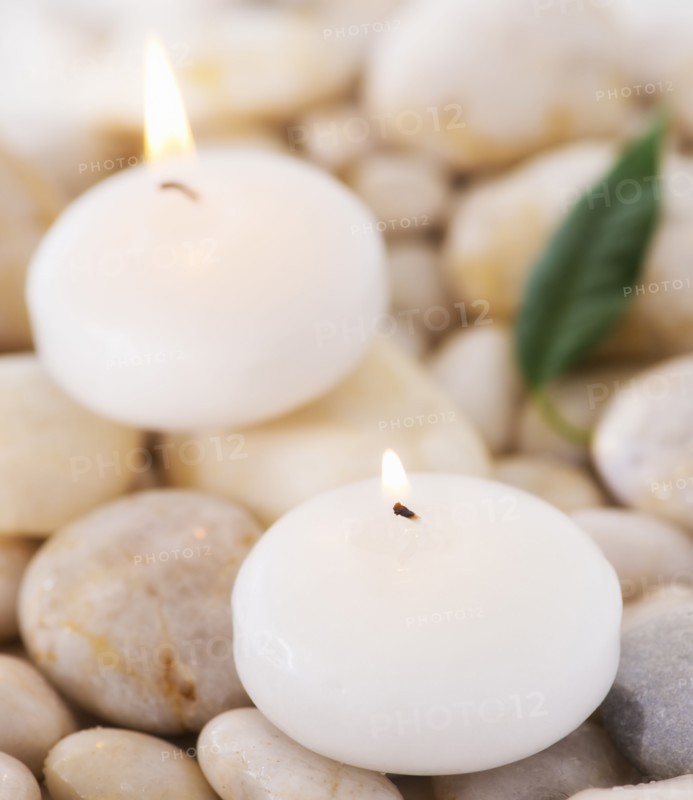Close up of tea lights and green leaf on pebble stones, studio shot. 
Photo: Daniel Grill