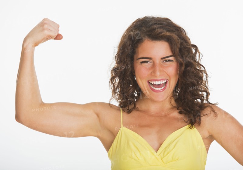 Portrait of young woman showing her biceps, studio shot. 
Photo: Daniel Grill