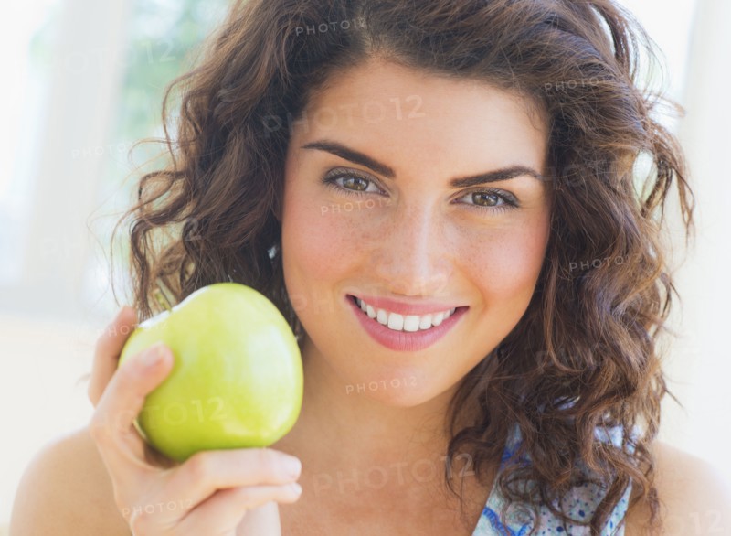 Portrait of smiling woman holding apple. 
Photo : Daniel Grill
