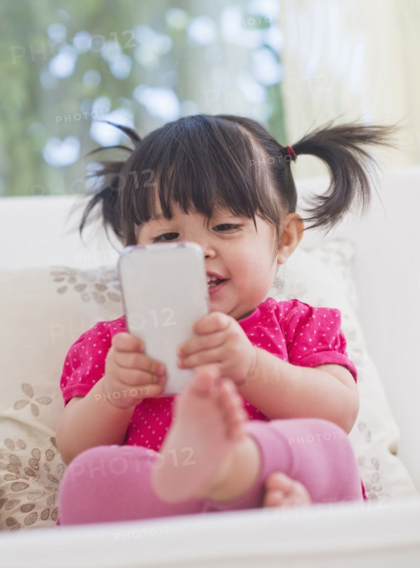 Baby girl (12-17 months) playing with mobile phone. 
Photo : Daniel Grill