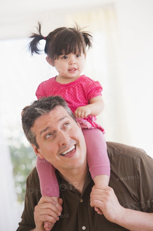 Father carrying baby daughter (12-17 months) on shoulders. 
Photo: Daniel Grill