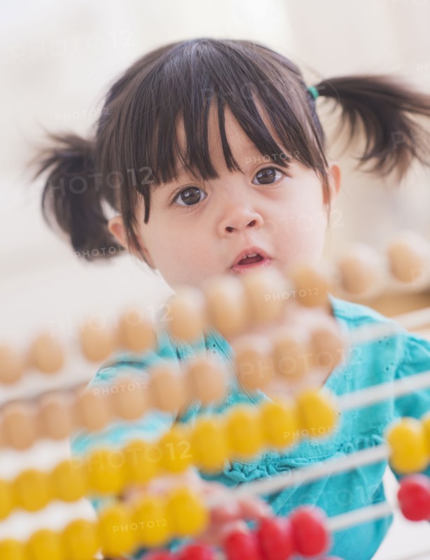 Portrait of baby girl (12-17 months) playing with abacus. 
Photo: Daniel Grill