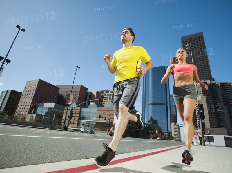 USA, California, Los Angeles, Young man and young woman running on city street.