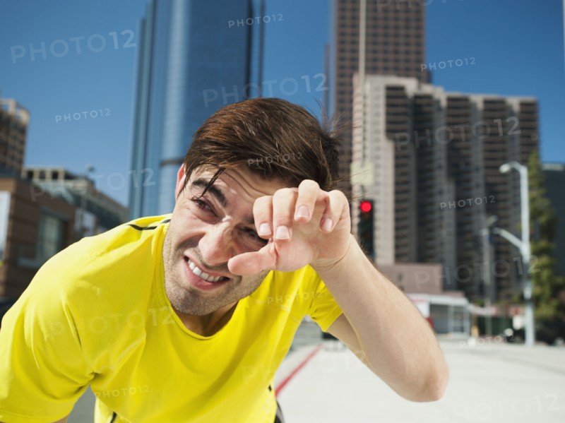 USA, California, Los Angeles, Young man resting after running on city street.