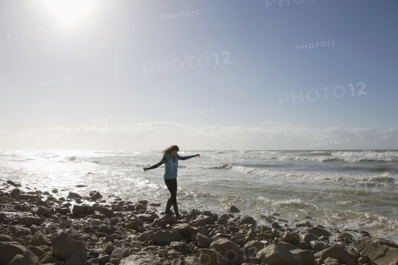 France, Pas-de-Calais, Escalles, Young woman strolling on rocky beach. 
Photo: Jan Scherders