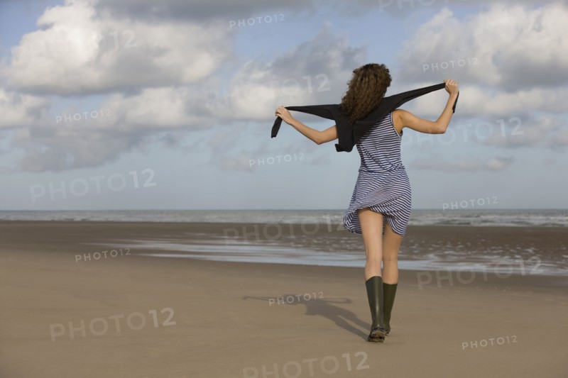France, Pas-de-Calais, Escalles, Young woman strolling on empty beach. 
Photo: Jan Scherders