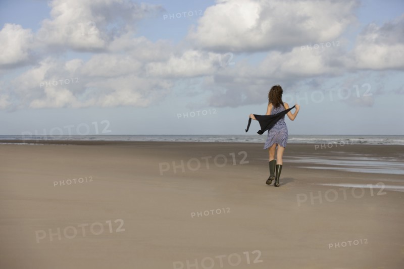 France, Pas-de-Calais, Escalles, Young woman strolling on empty beach. 
Photo: Jan Scherders