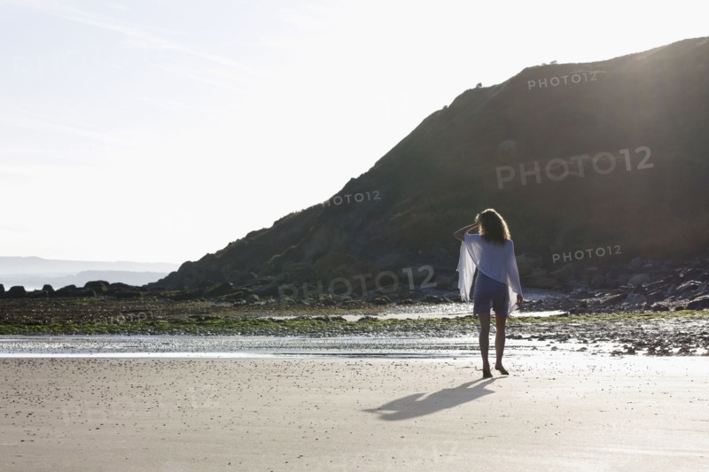 France, Pas-de-Calais, Escalles, Young woman strolling on empty beach. 
Photo: Jan Scherders