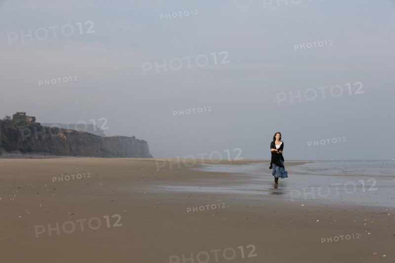 France, Pas-de-Calais, Escalles, Young woman strolling on empty beach. 
Photo : Jan Scherders