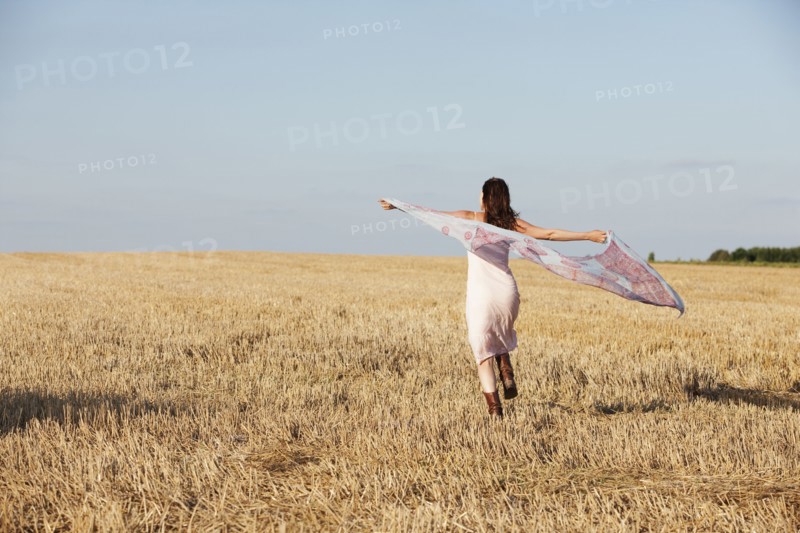 France, Picardie, Albert, Young woman running through stubble with shawl. 
Photo: Jan Scherders
