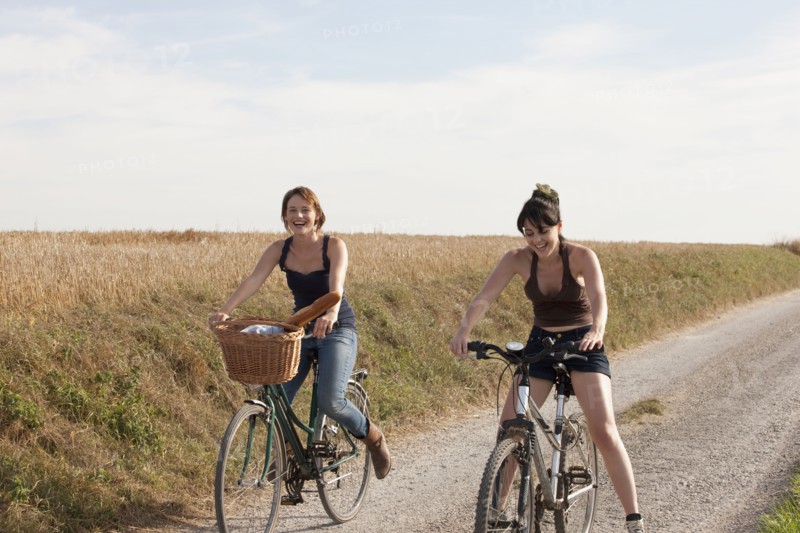 France, Picardie, Albert, Young women on bikes on country road. 
Photo : Jan Scherders