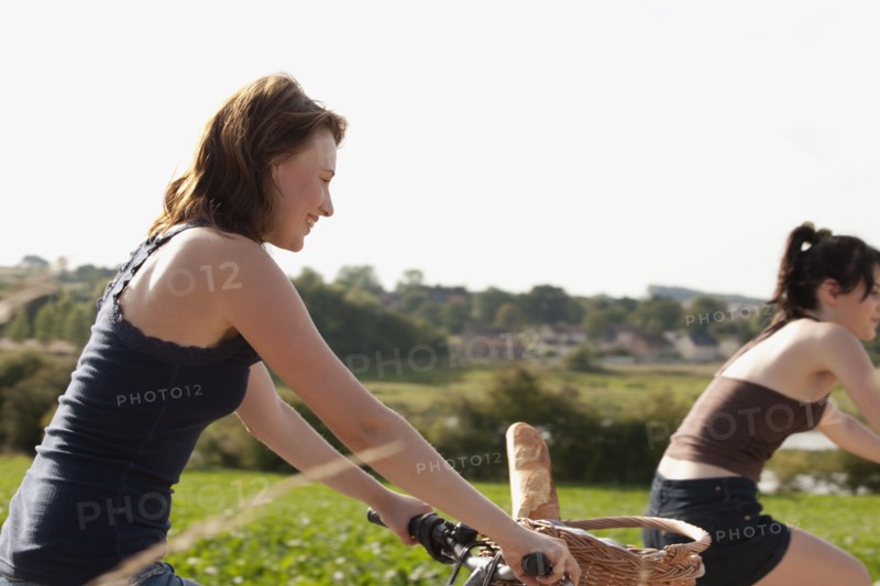 France, Picardie, Albert, Young women on bikes on country road. 
Photo : Jan Scherders