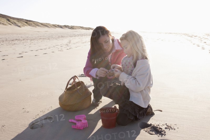 Mother with daughter collecting shells on beach. 
Photo : Jan Scherders