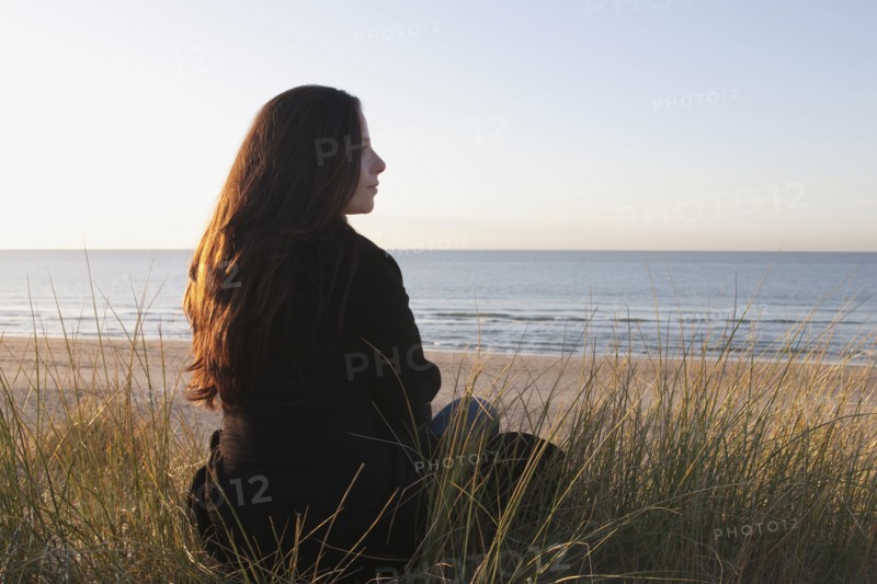 Netherlands, Zeeland, Haamstede, Woman relaxing on sand dune. 
Photo: Jan Scherders