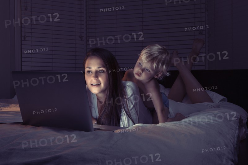 Mother with son using laptop in bed. 
Photo : King Lawrence