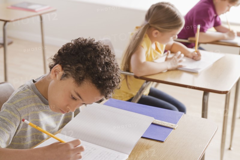 Schoolchildren focused on writing in classroom. 
Photo : Rob Lewine