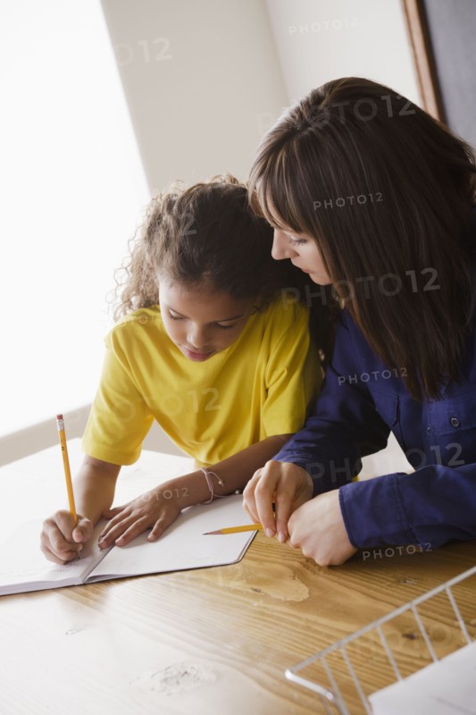 Schoolgirl writing with teacher in classroom. 
Photo: Rob Lewine