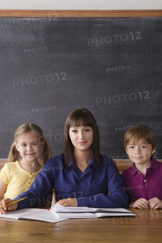 Teacher sitting by desk with two pupils. 
Photo: Rob Lewine