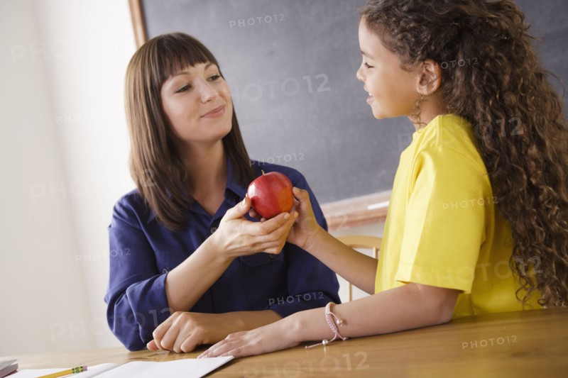 Teacher receiving apple from schoolgirl. 
Photo: Rob Lewine
