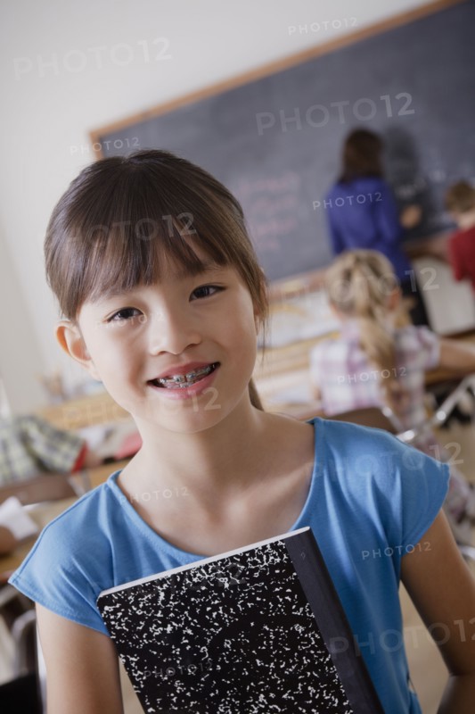 Portrait of schoolgirl holding notebook. 
Photo : Rob Lewine
