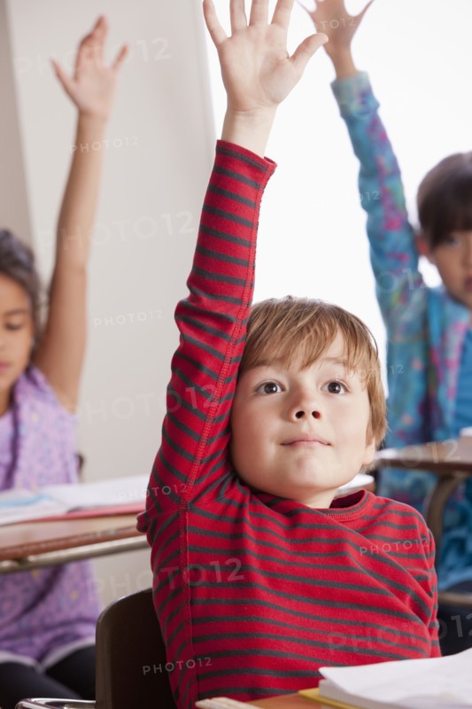 Pupils in classroom raising hands. 
Photo: Rob Lewine