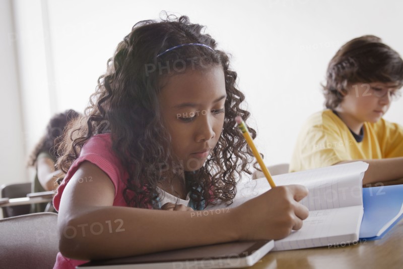Portrait of schoolgirl (10-11) writing. 
Photo : Rob Lewine