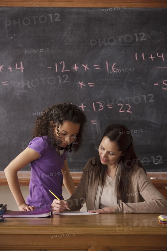 Schoolgirl (10-11) and teacher with blackboard in background. 
Photo : Rob Lewine