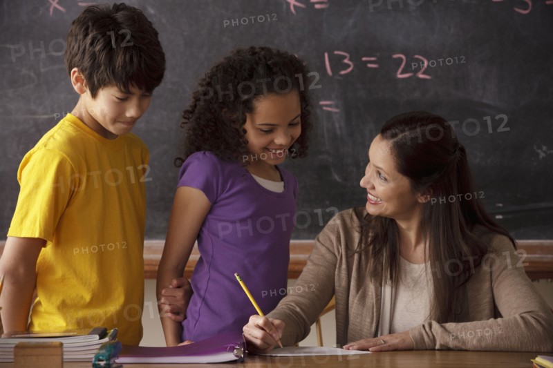 Teacher explaining exercise to schoolgirl (10-11) and schoolboy (12-13). 
Photo : Rob Lewine