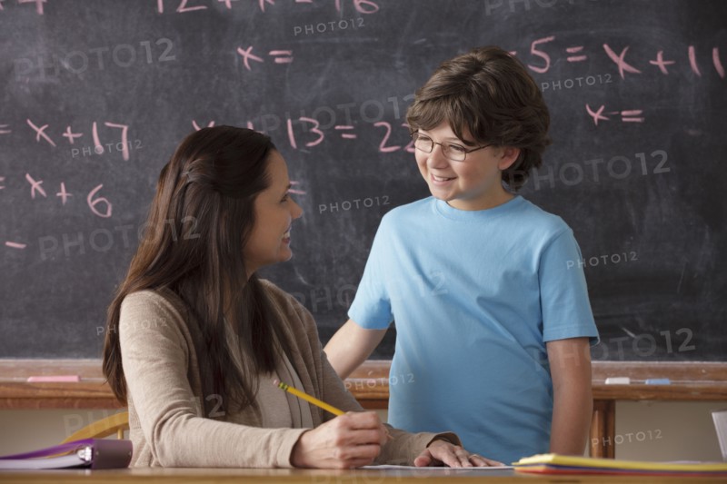 Schoolboy (10-11) and teacher face to face with blackboard in background. 
Photo: Rob Lewine