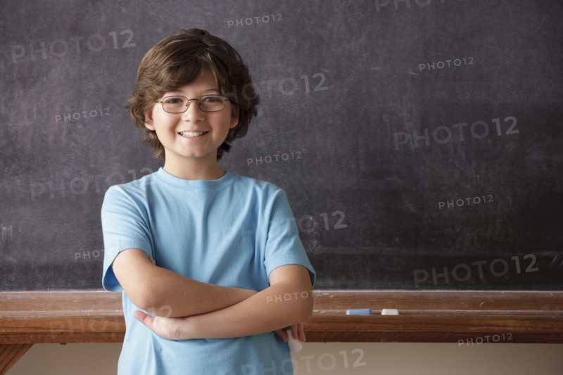 Portrait of schoolboy (10-11) in front of blackboard. 
Photo : Rob Lewine