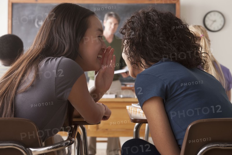 Teenage girls (14-15,16-17) whispering in classroom. 
Photo : Rob Lewine