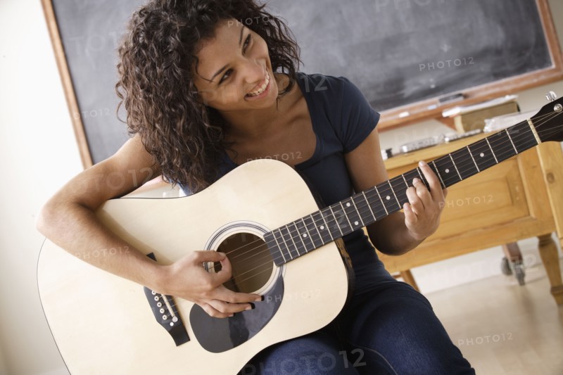Teenage girl (16-17) playing guitar. 
Photo : Rob Lewine