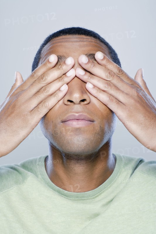 Young man with hands covering eyes, studio shot. 
Photo: Rob Lewine