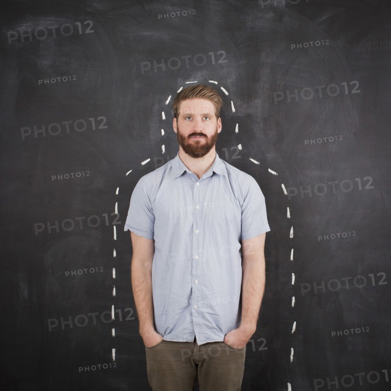 Young man with chalk outline on blackboard, studio shot. 
Photo : Jessica Peterson