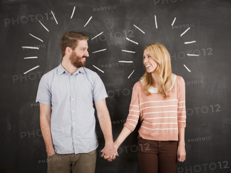 Young couple with blackboard in background, studio shot. 
Photo : Jessica Peterson
