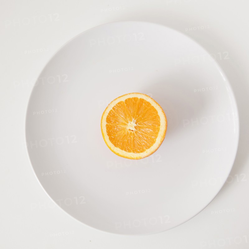 Half of orange on plate, studio shot. 
Photo : Jessica Peterson