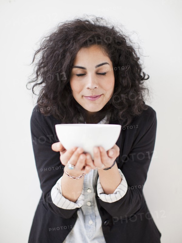 Studio shot of young woman holding white bowl. 
Photo : Jessica Peterson