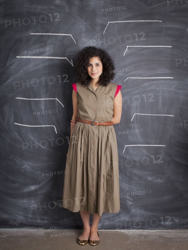 Young teacher posing against blackboard with blank lines written in chalk. 
Photo: Jessica Peterson