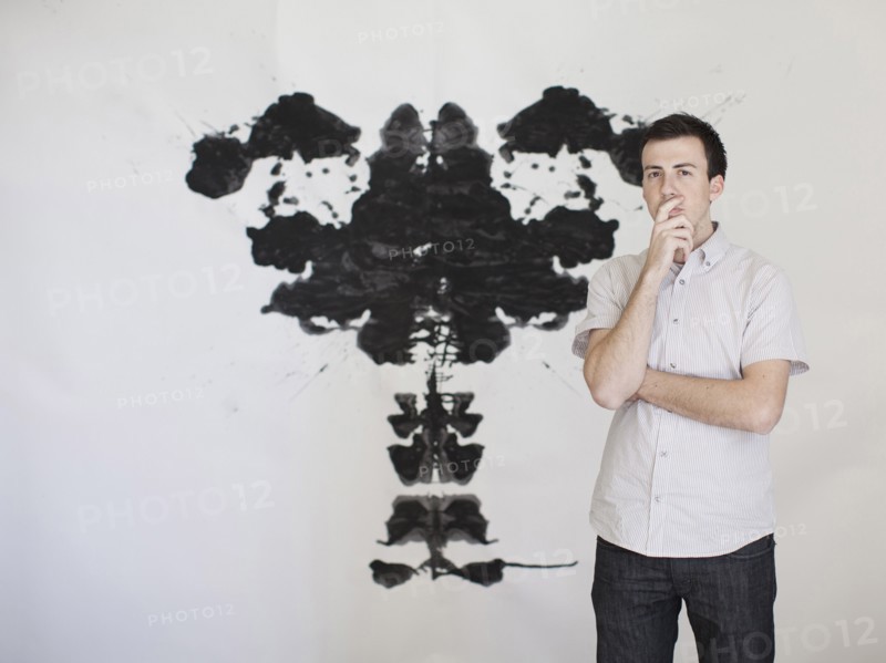Man looking standing in front of complex shape painted on wall. 
Photo : Jessica Peterson