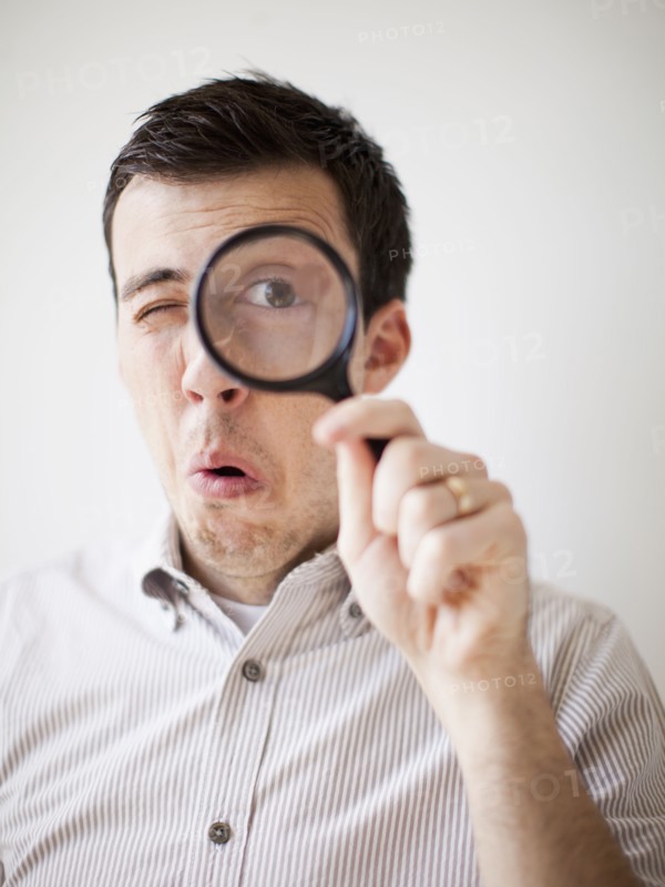 Man looking through magnifying glass. 
Photo : Jessica Peterson