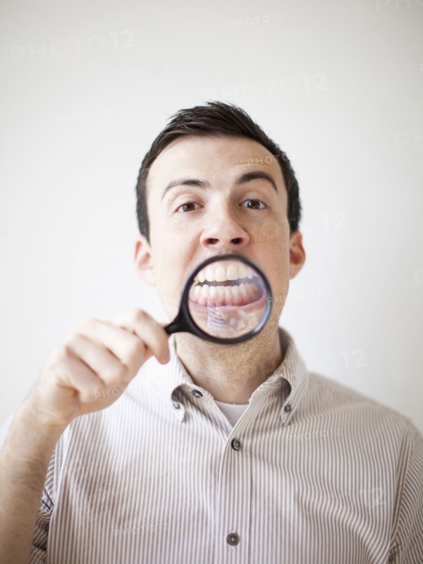 Man looking standing looking through magnifying glass. 
Photo: Jessica Peterson