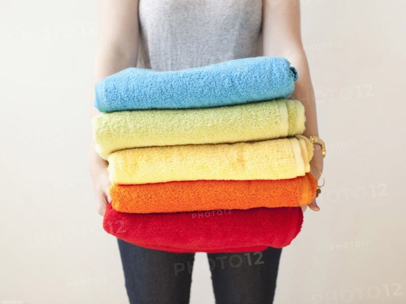 Young woman holding stack of towels. 
Photo : Jessica Peterson