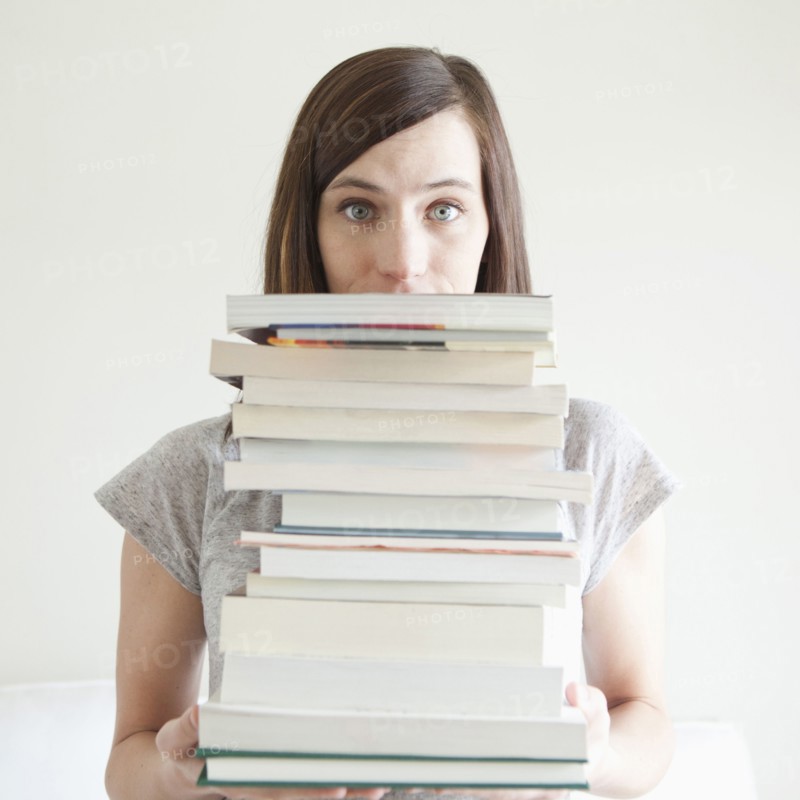 Young woman holding stack of books. 
Photo : Jessica Peterson