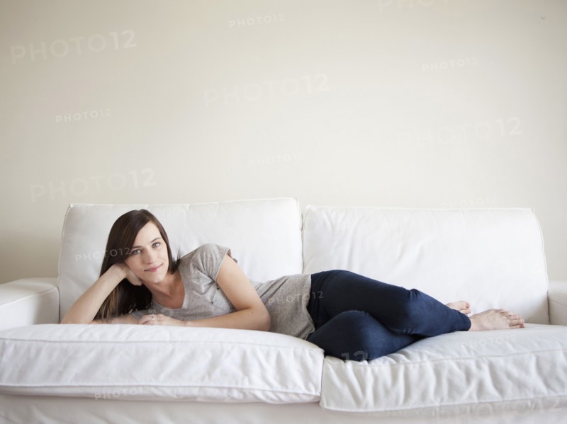 Happy young woman reclining on bed. 
Photo: Jessica Peterson