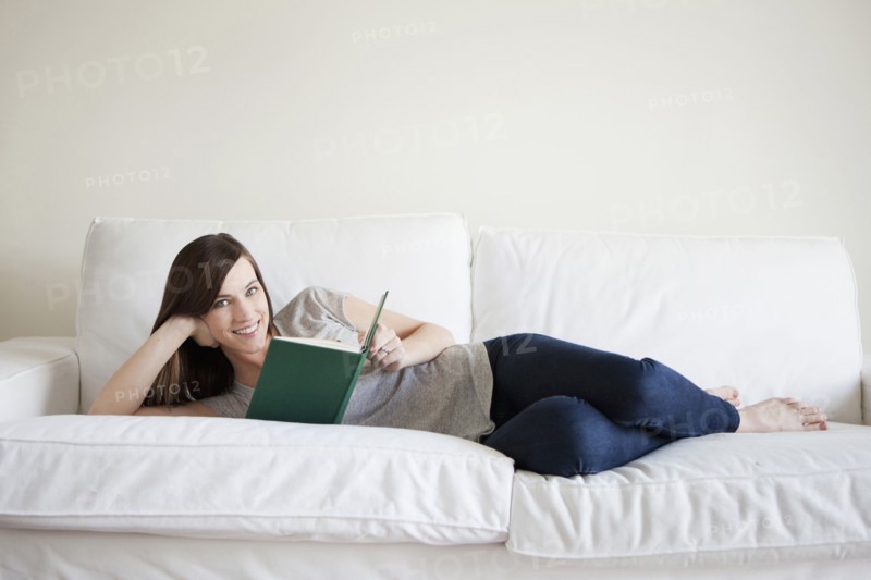 Young woman reclining on bed, reading book. 
Photo: Jessica Peterson