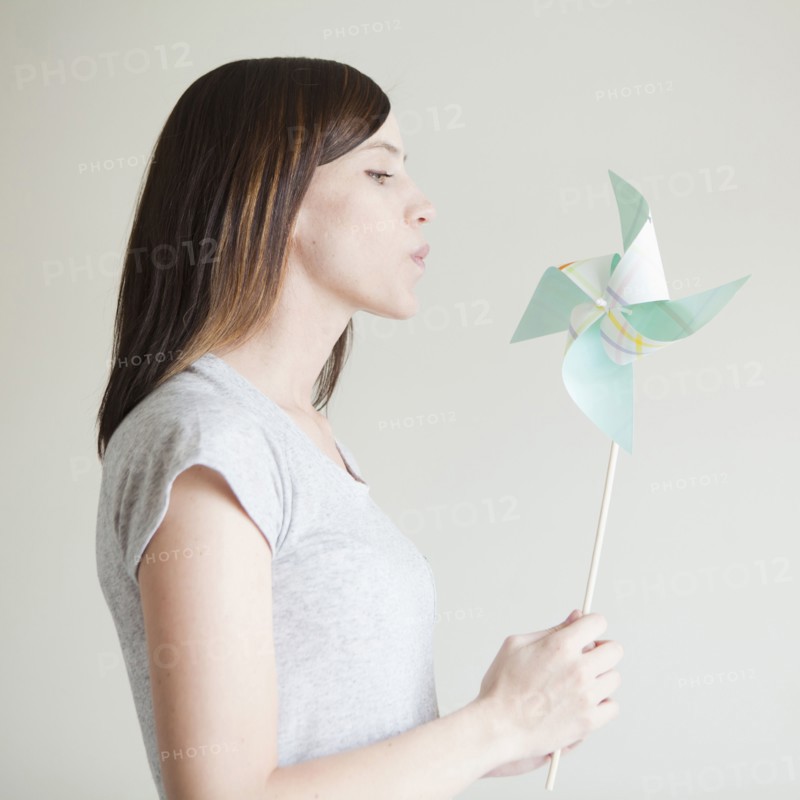 Young woman blowing at paper fan. 
Photo : Jessica Peterson