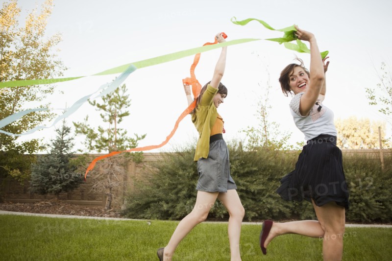 Two happy female friends playing in domestic garden. 
Photo : Jessica Peterson