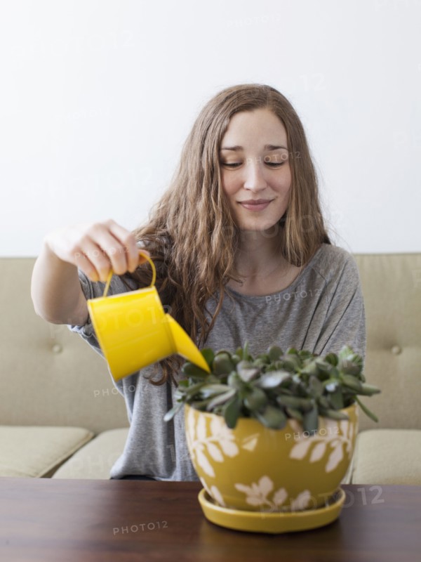 Young woman watering pot plant . 
Photo: Jessica Peterson