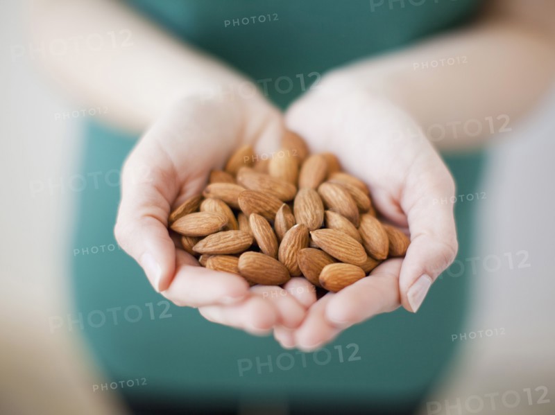 Studio shot of woman showing handful of almonds. 
Photo: Jessica Peterson